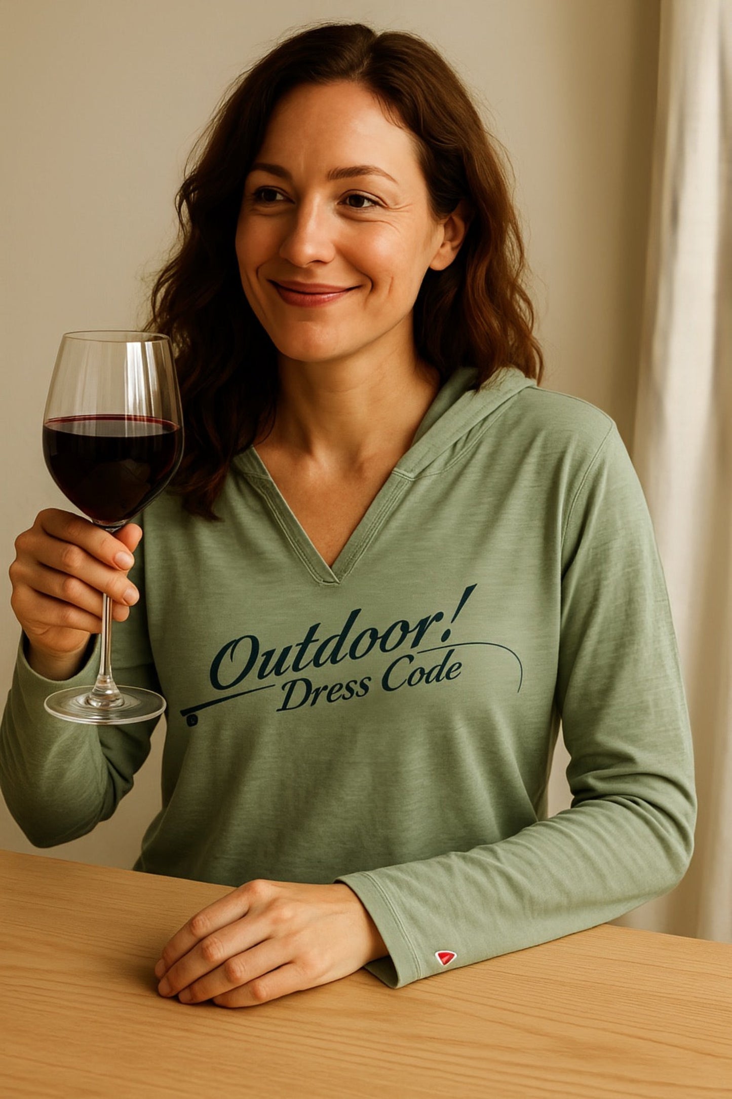 Woman wearing a green shirt with 'Outdoor! Dress Code' text, holding a glass of red wine.