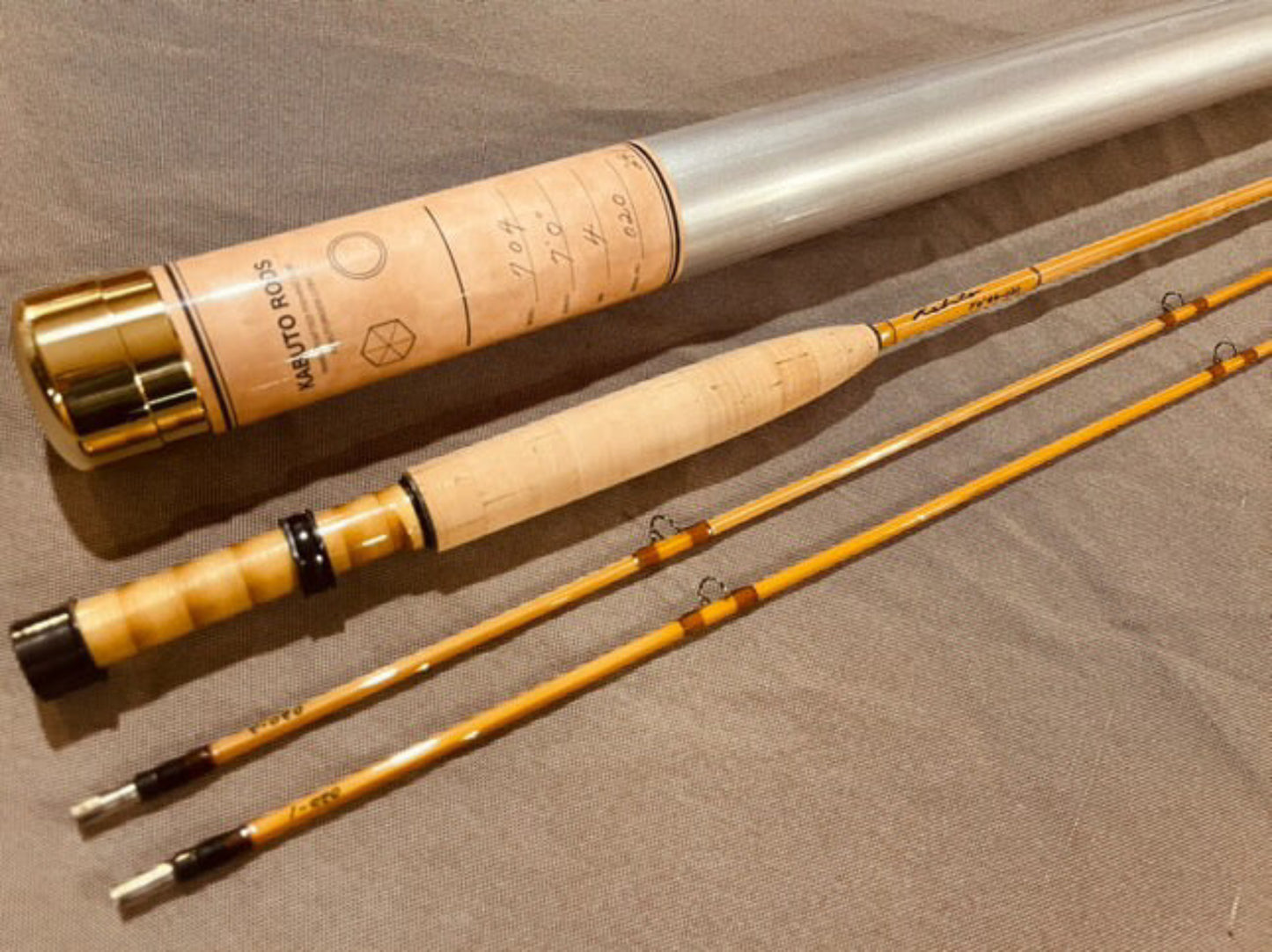 Fishing rod with cork handle and gold accents on a brown surface