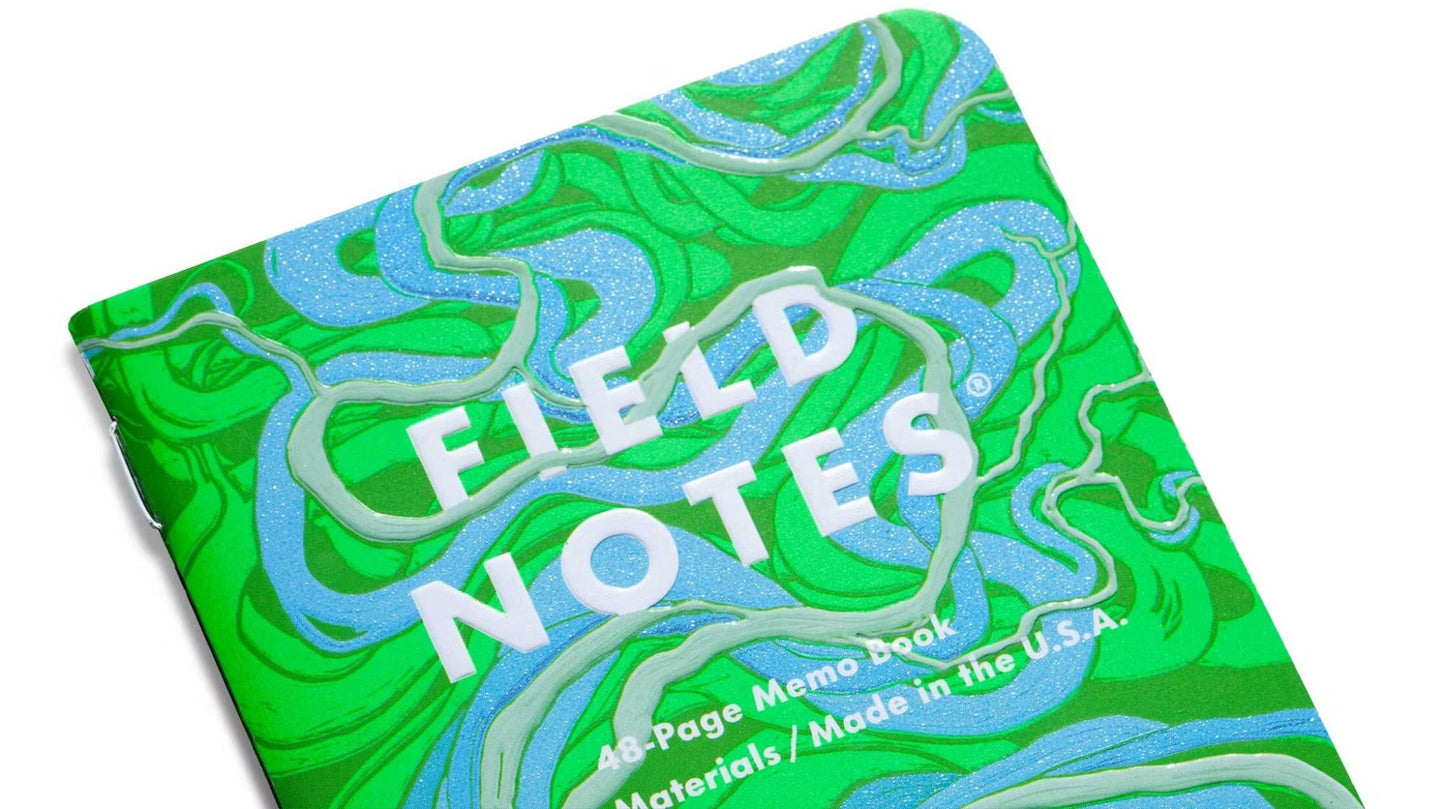 Green and blue Field Notes notebook on a white background