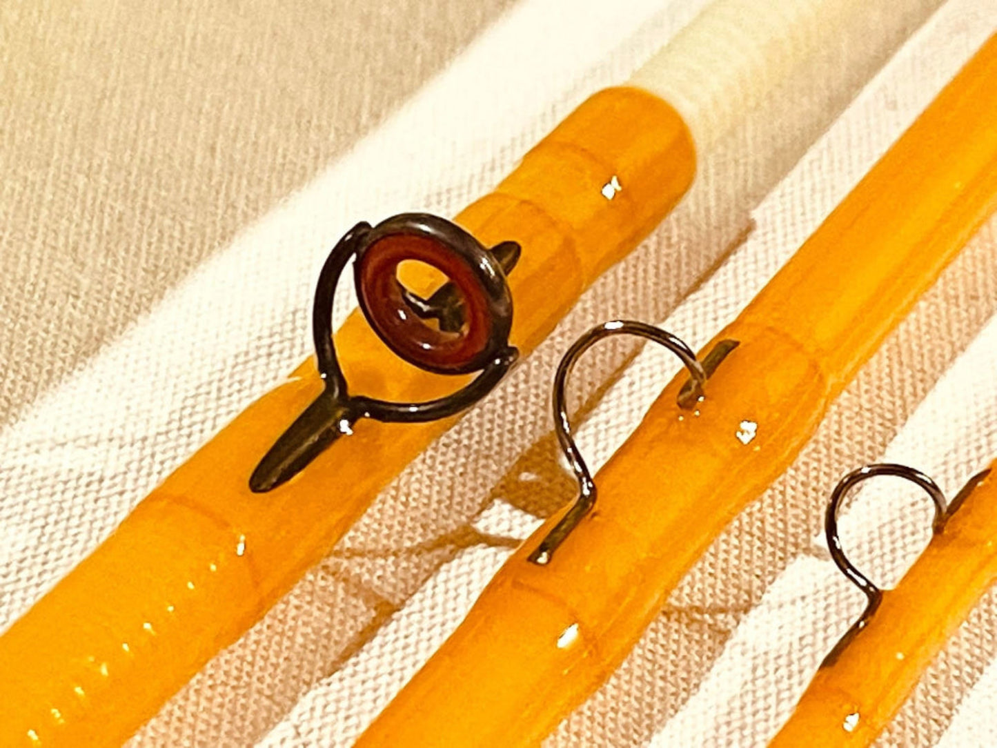 A precision-crafted yellow fly rod, 8 feet in length, designed for expert anglers. The rod features a stacked bamboo reel seat, adding a classic touch to its fiberglass construction. Its moderate action and light power offer smooth casting for fly fishing enthusiasts.