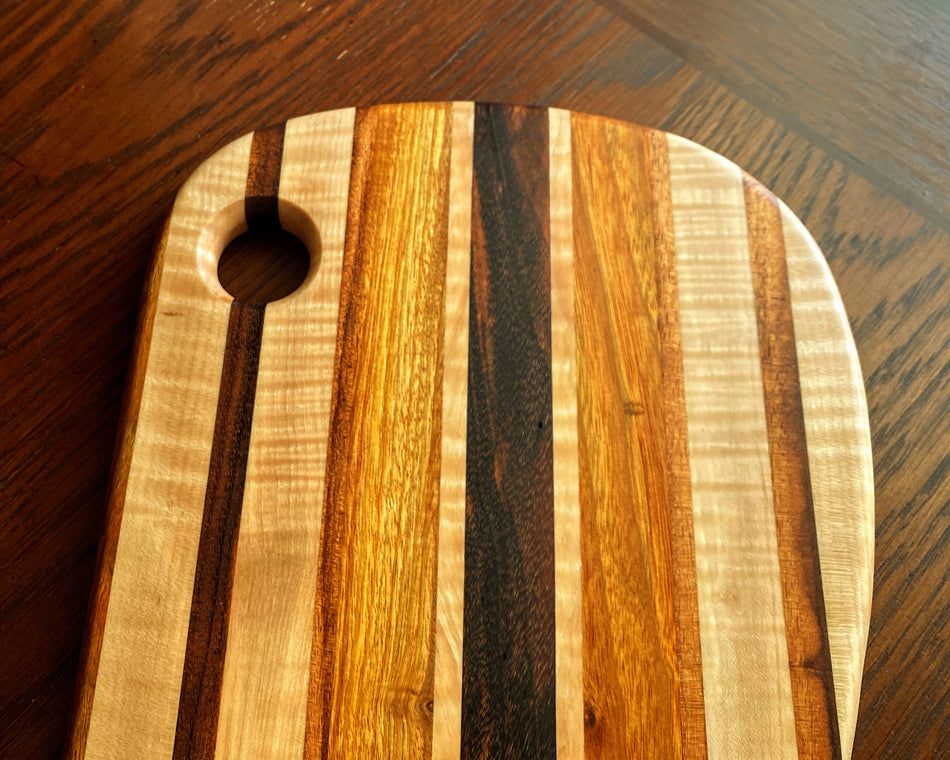 This charcuterie board is crafted with three types of wood: Carnary, Tiger Maple, and Goncalo Alves. It makes a stylish presentation for last-minute gatherings and has been expertly seasoned. It is sealed with Sutherland Welles Ltd.® Millie's All-Purpose Penetrating Tung Oil.