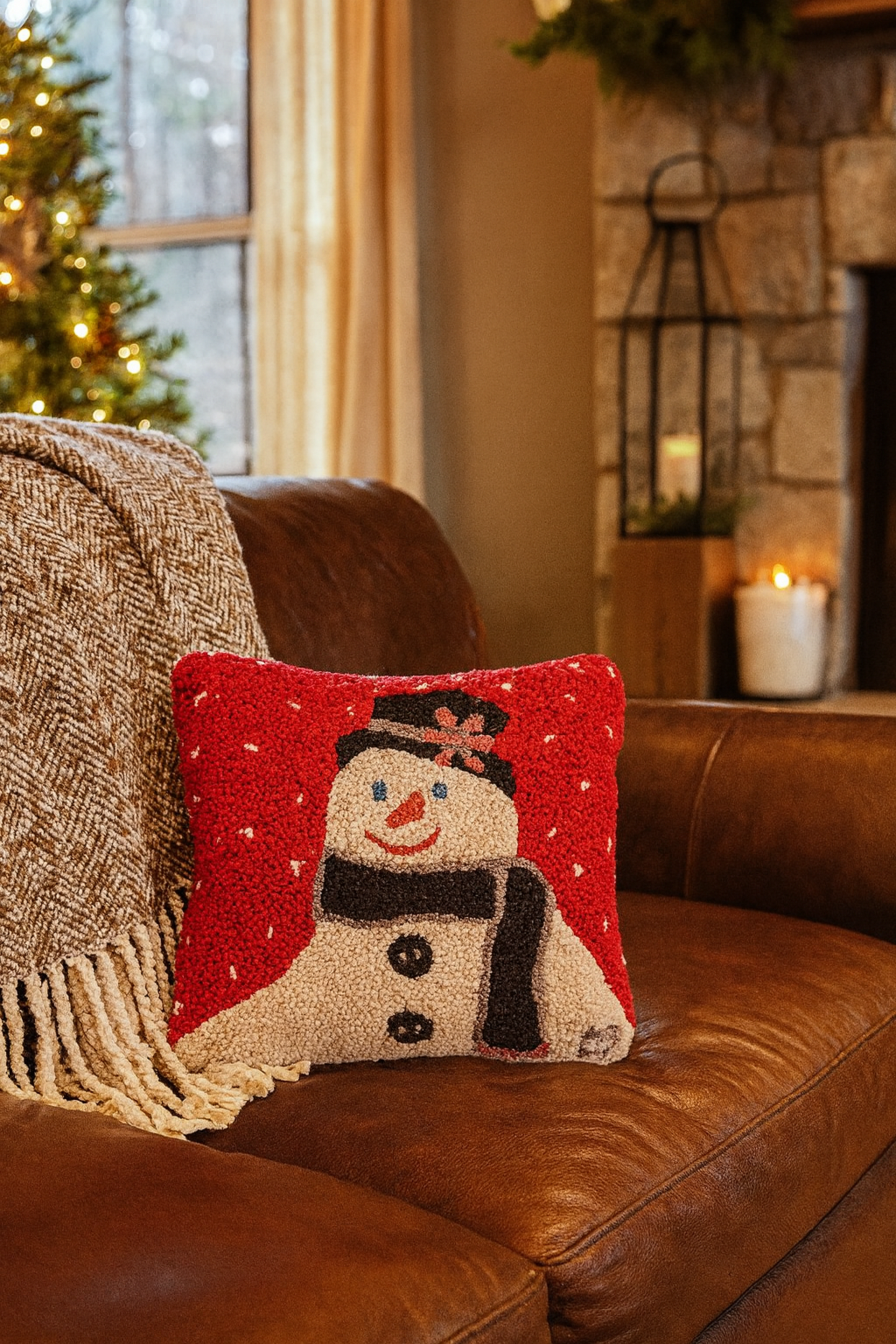 Decorative pillow with a snowman design on a brown couch in a cozy living room.