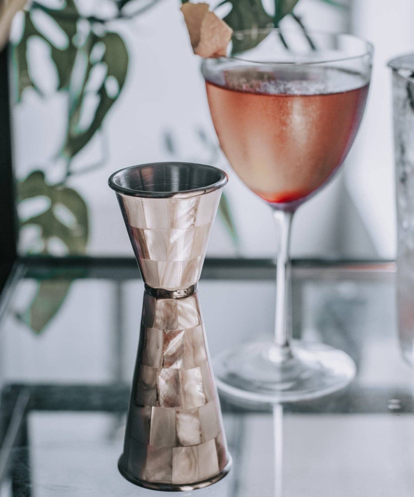 Metallic jigger and glass with a pink cocktail on a blurred background