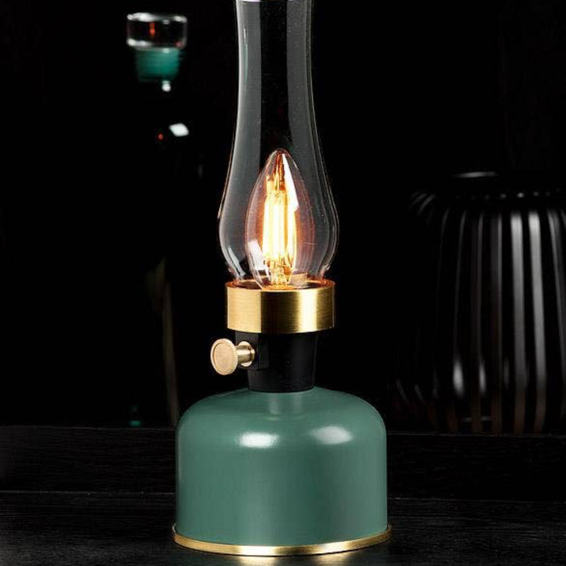 Vintage-style oil lamp with a green base and clear glass chimney on a dark background