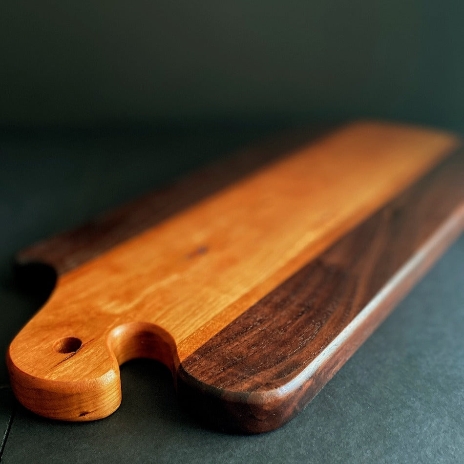 The Handcrafted Charcuterie Board is crafted from Gummy Cherry, Cherry and Walnut measuring 18 x 8 x 1. This combination of woods offers remarkable depth. It is then seasoned with Milie's Tung Oil.