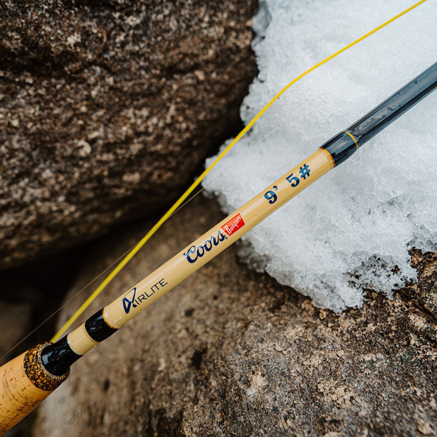 Fishing rod with brand logos on a snowy ground and rock background