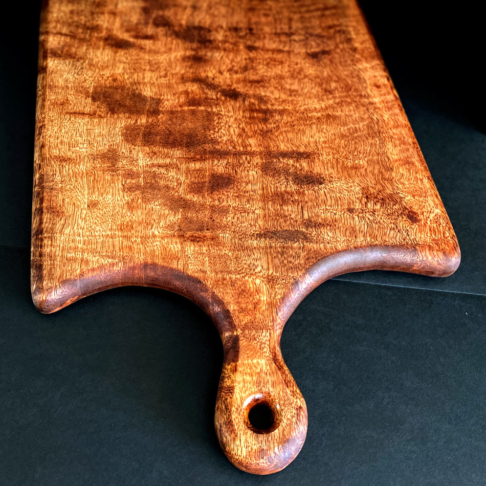 
                      
                        This Board was crafted from Curly Mango and displays a live edge with intricate detailing to retain its character and luster. The Curly Mango's captivating colors are awe-inspiring and abundant surface area to create an incredible charcuterie board.
                      
                    