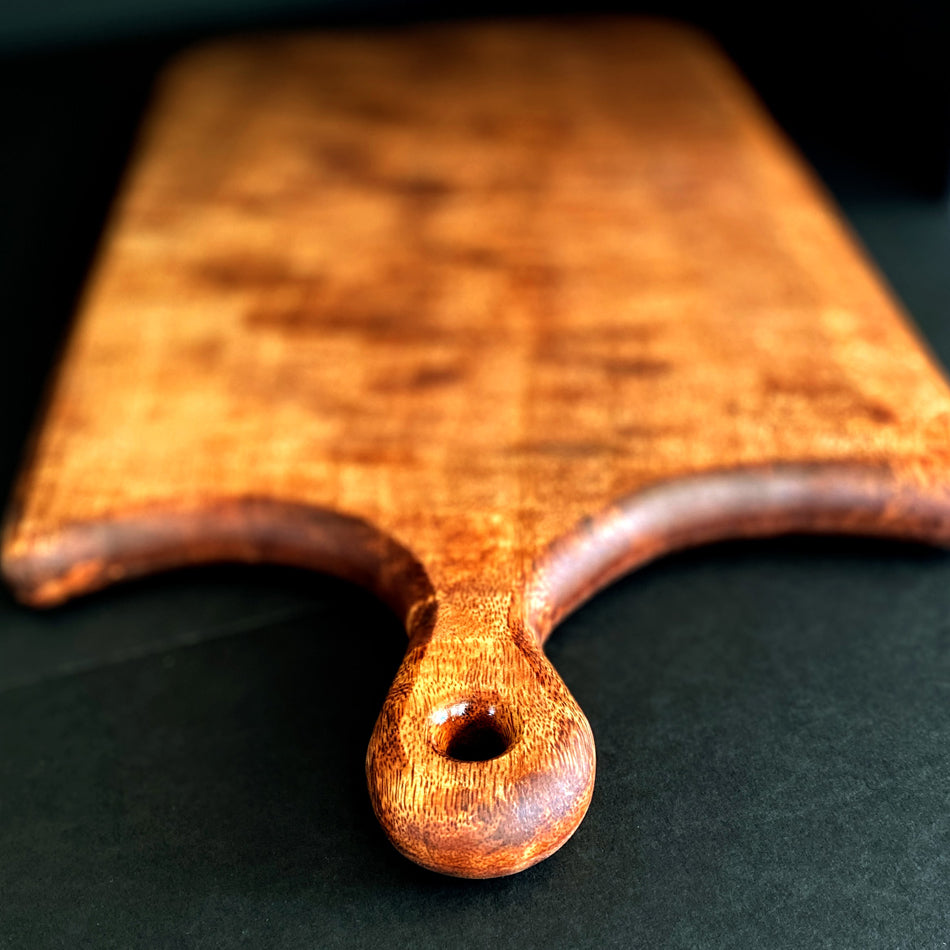 
                      
                        This Board was crafted from Curly Mango and displays a live edge with intricate detailing to retain its character and luster. The Curly Mango's captivating colors are awe-inspiring and abundant surface area to create an incredible charcuterie board.
                      
                    