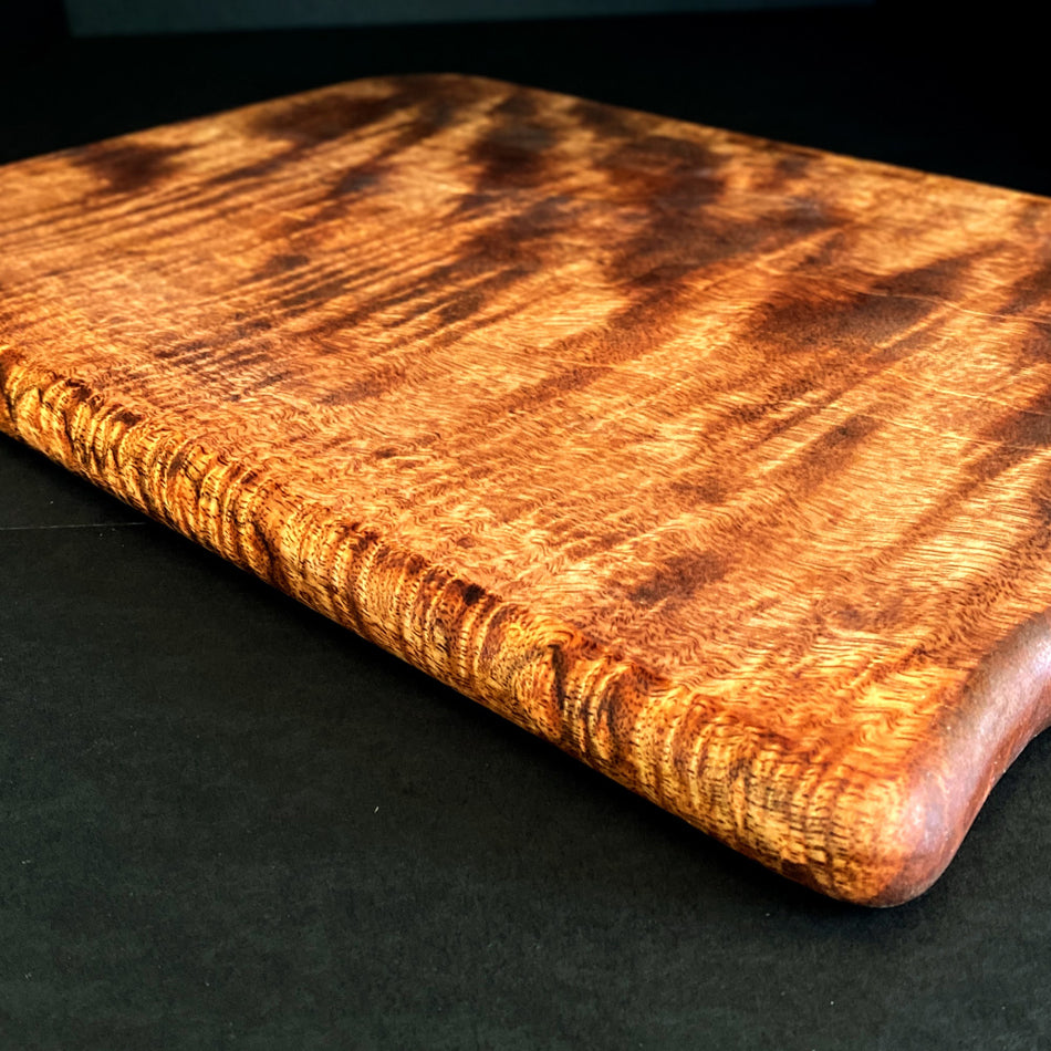 
                      
                        This Board was crafted from Curly Mango and displays a live edge with intricate detailing to retain its character and luster. The Curly Mango's captivating colors are awe-inspiring and abundant surface area to create an incredible charcuterie board.
                      
                    