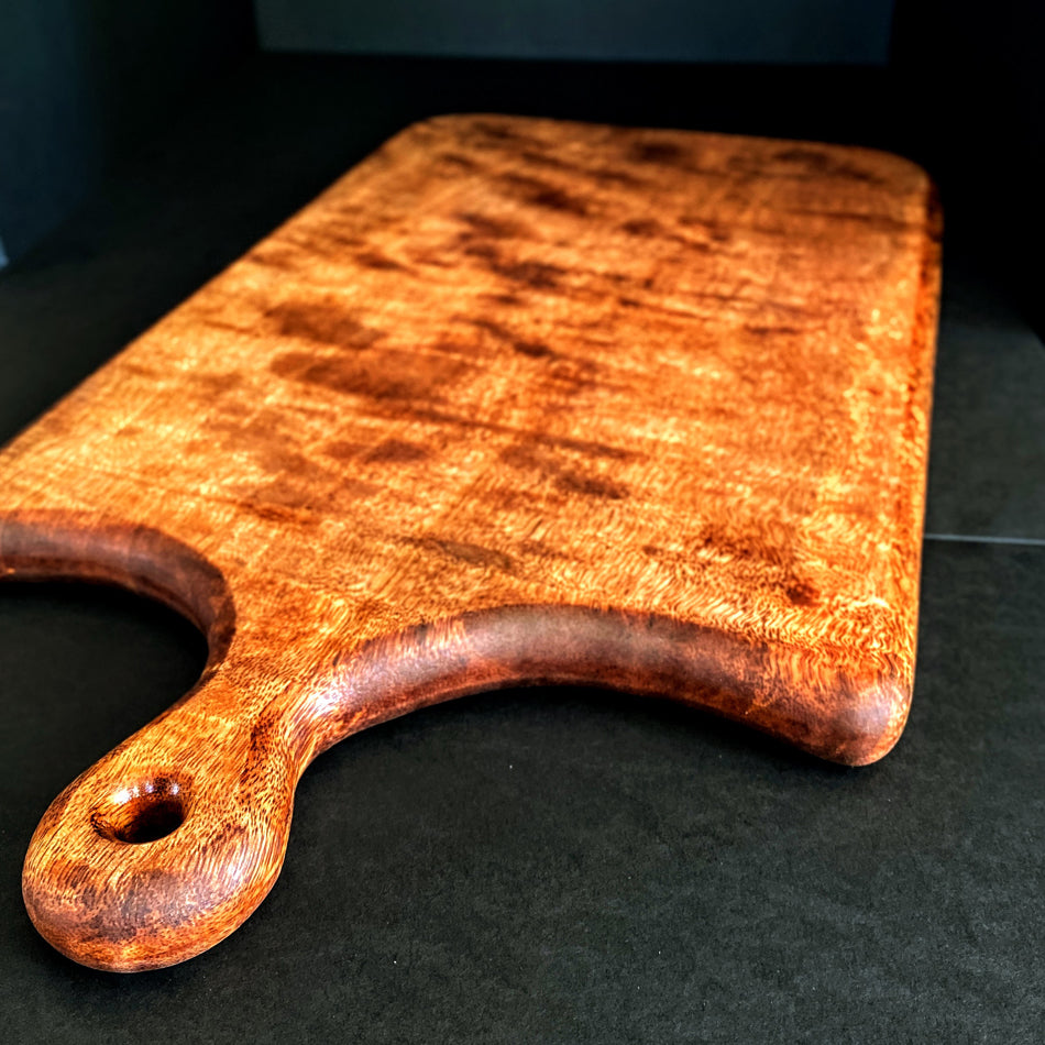 
                      
                        This Board was crafted from Curly Mango and displays a live edge with intricate detailing to retain its character and luster. The Curly Mango's captivating colors are awe-inspiring and abundant surface area to create an incredible charcuterie board.
                      
                    