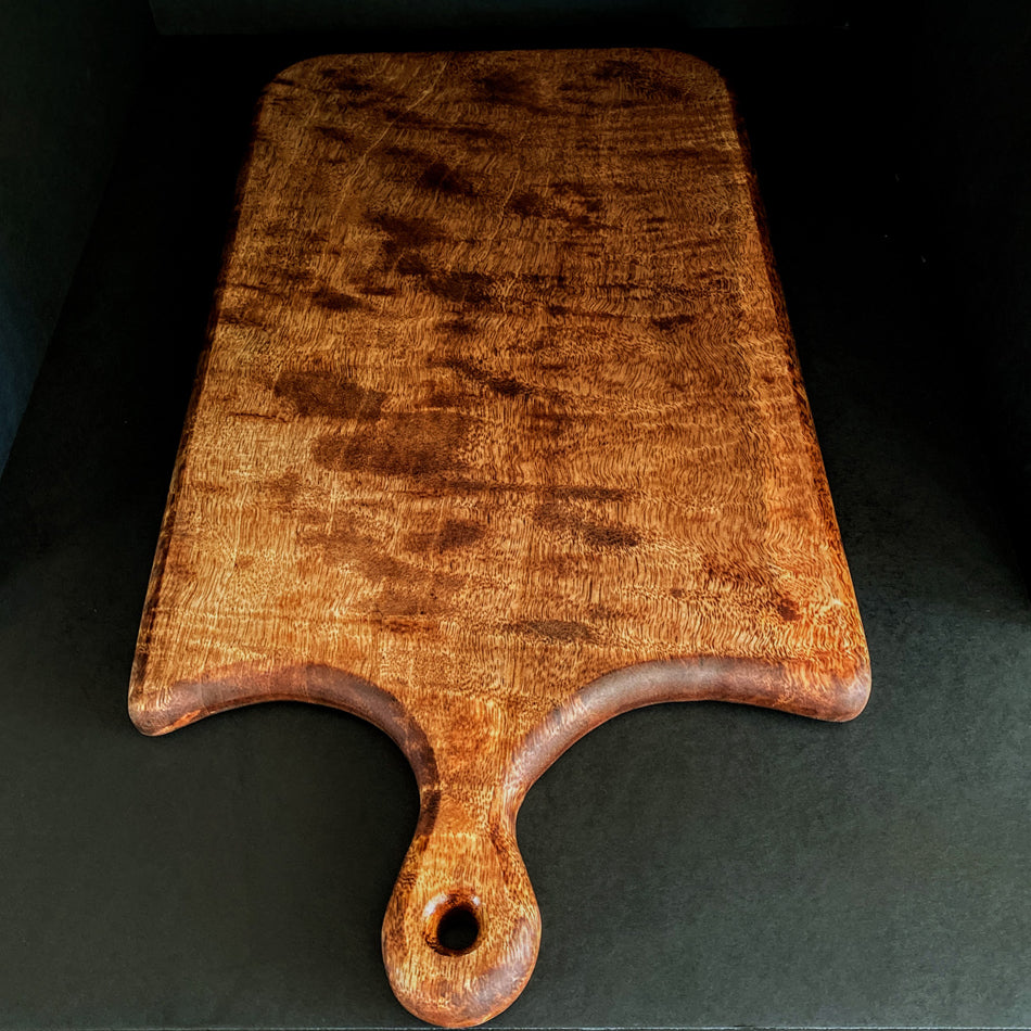 This Board was crafted from Curly Mango and displays a live edge with intricate detailing to retain its character and luster. The Curly Mango's captivating colors are awe-inspiring and abundant surface area to create an incredible charcuterie board.