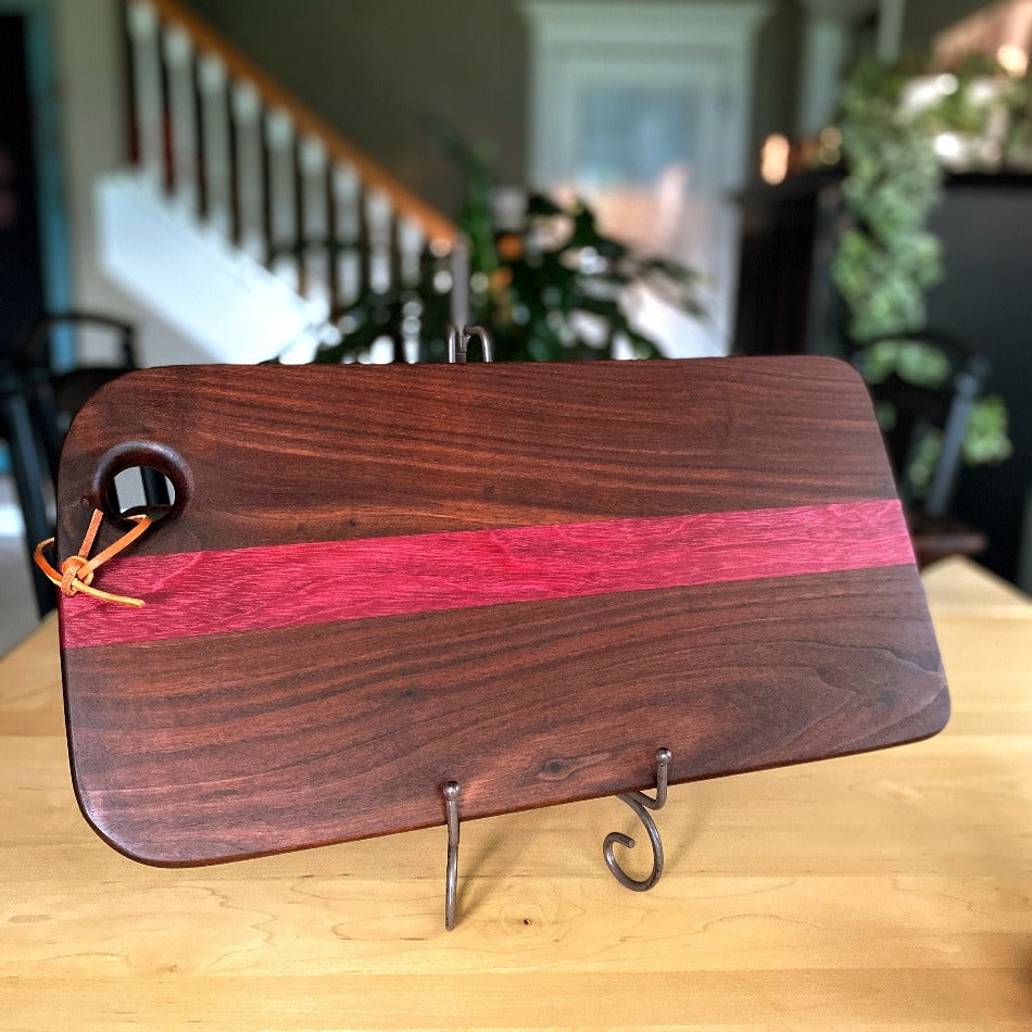 This handcrafted charcuterie board is the perfect way to impress guests. It's made with walnut and purple heart wood to create a stunning contrast of colors, which adds a simple, yet elegant touch to any presentation.