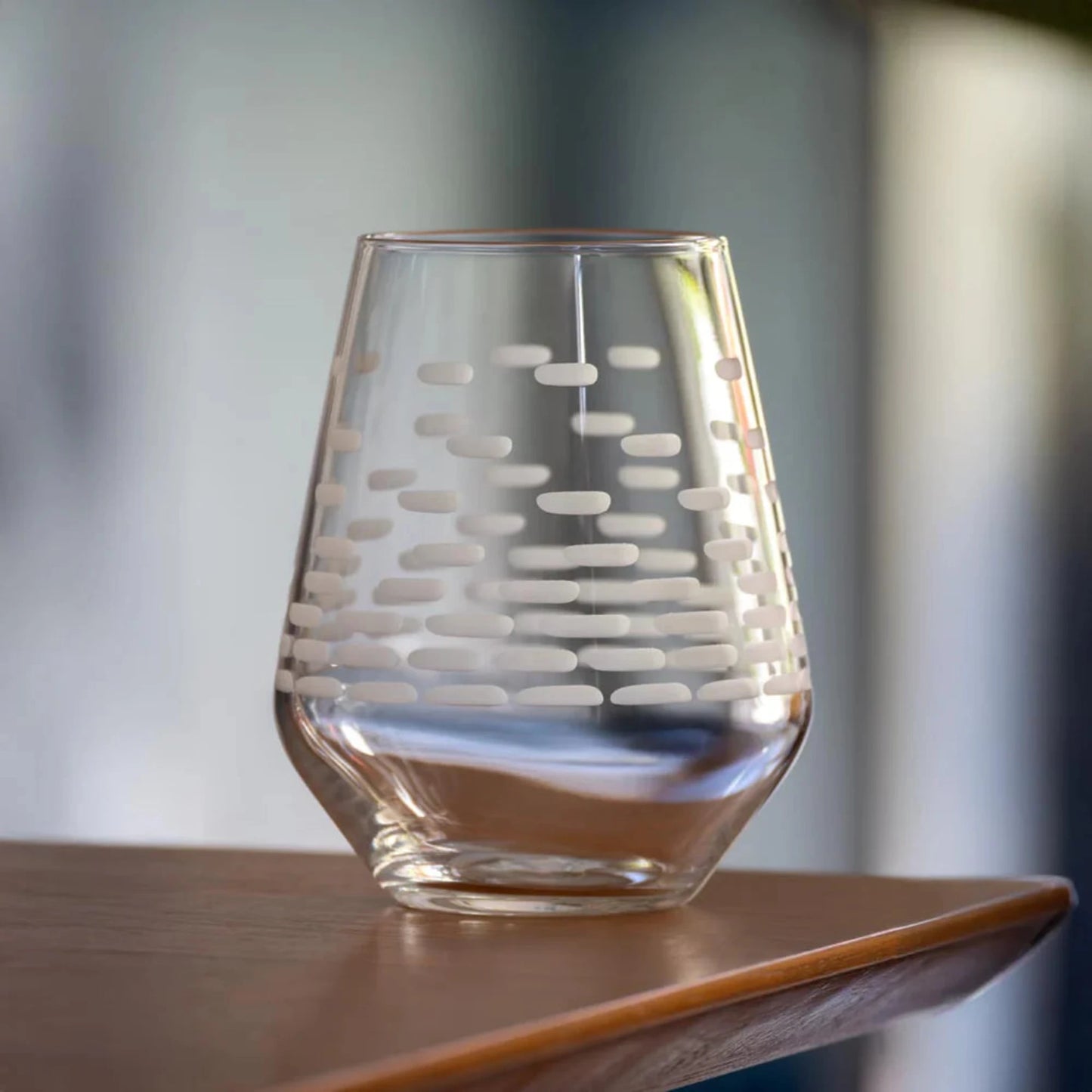 Clear glass with etched design on a wooden surface