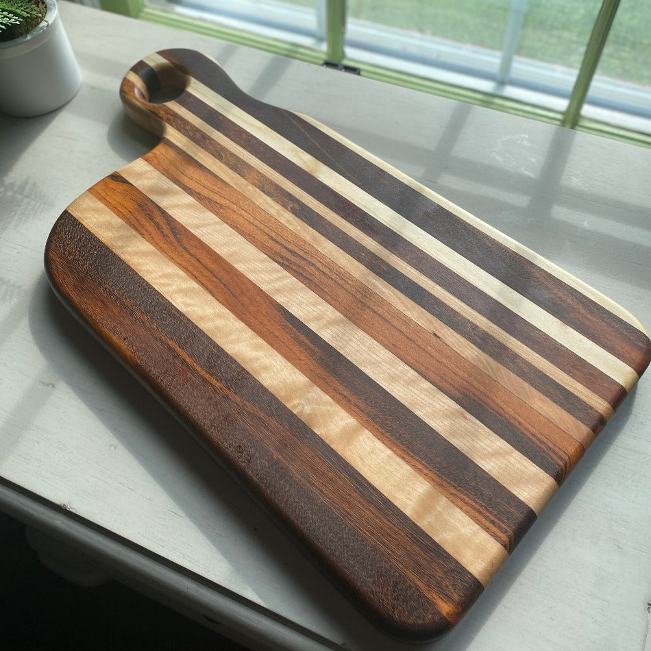 
                  
                    Composed of Tiger Heart, Goncalo Alves and Black Limba, the 19" long, 10" wide, Handcrafted Charcuterie Board is a stunning 1" thick spectacle of contrast and color.
                  
                