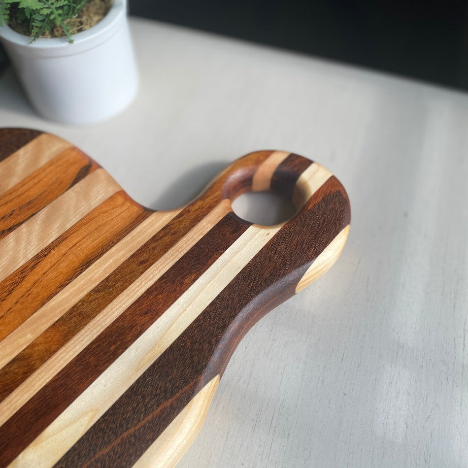 
                  
                    Composed of Tiger Heart, Goncalo Alves and Black Limba, the 19" long, 10" wide, Handcrafted Charcuterie Board is a stunning 1" thick spectacle of contrast and color.
                  
                