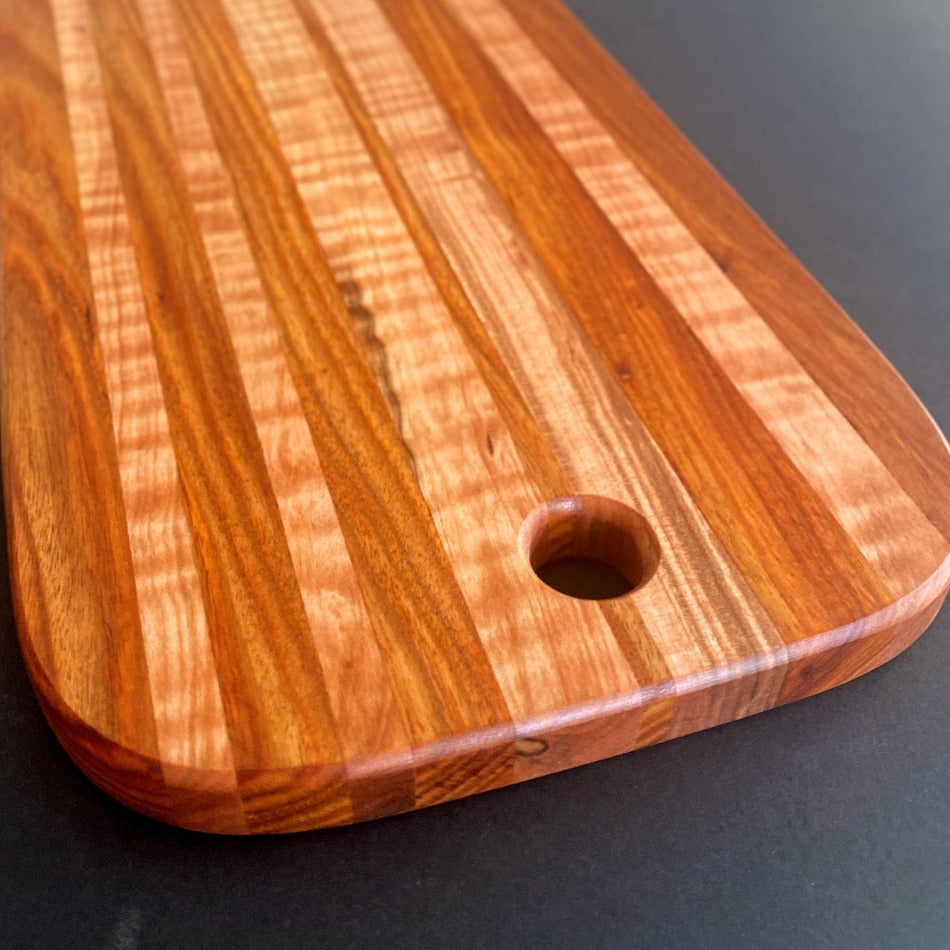 The Handcrafted Charcuterie Board or Bread Board is crafted from Tiger Maple and Canary Wood, measuring 18 x 8 x 1. This combination of woods offers remarkable depth. It is then seasoned with Milie's Tung Oil.