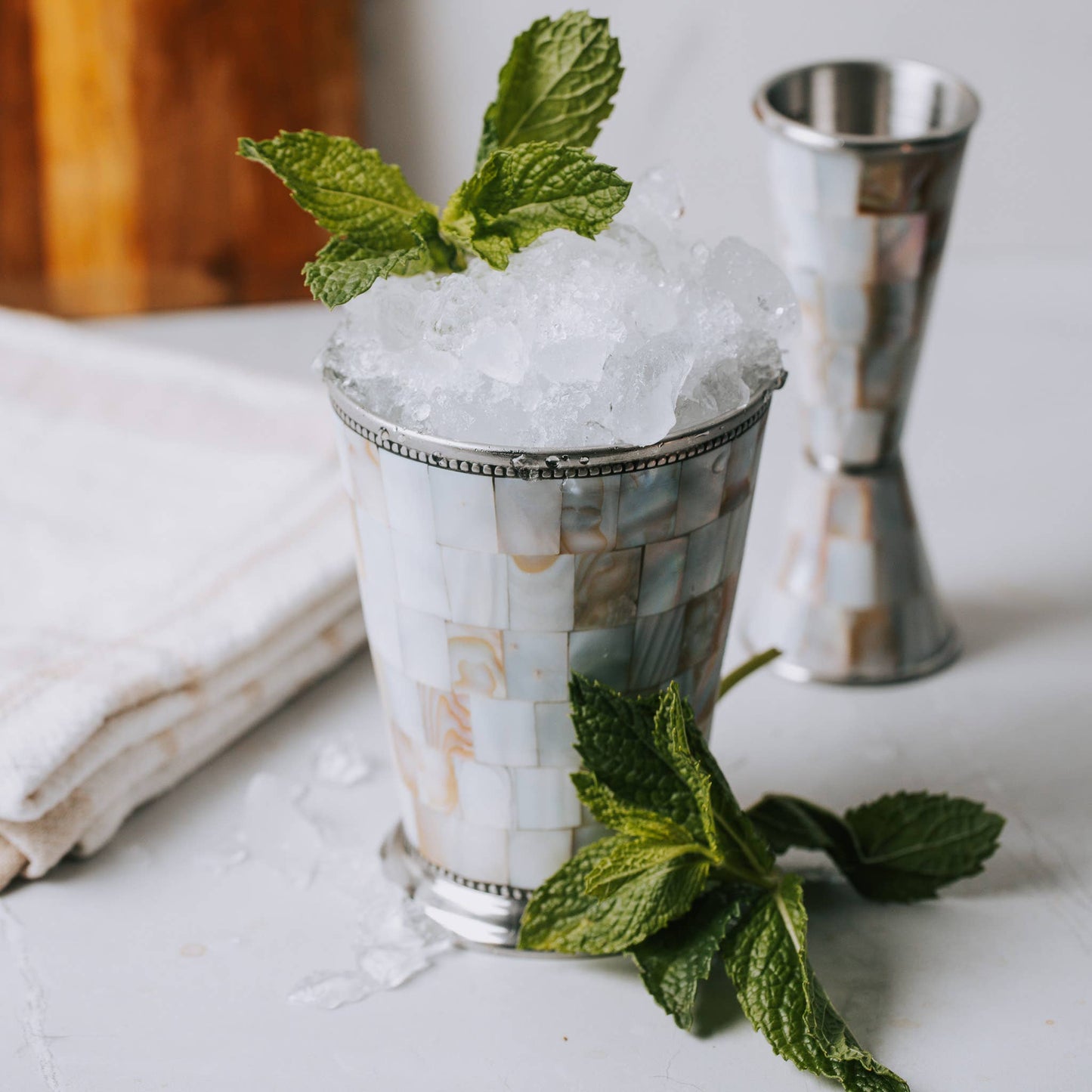Mint julep with crushed ice and mint leaves on a white surface