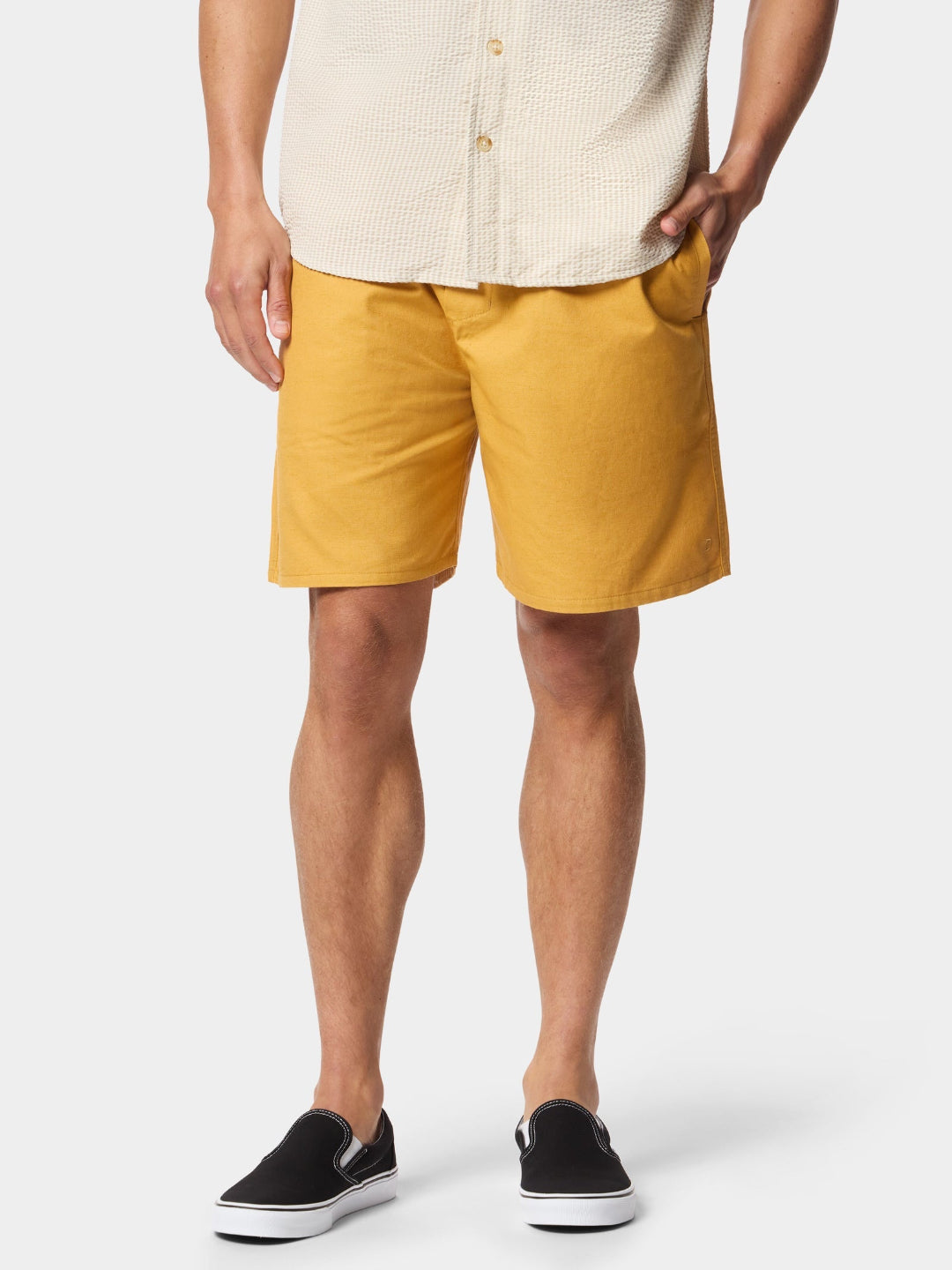 Person wearing mustard yellow shorts and a cream shirt on a white background