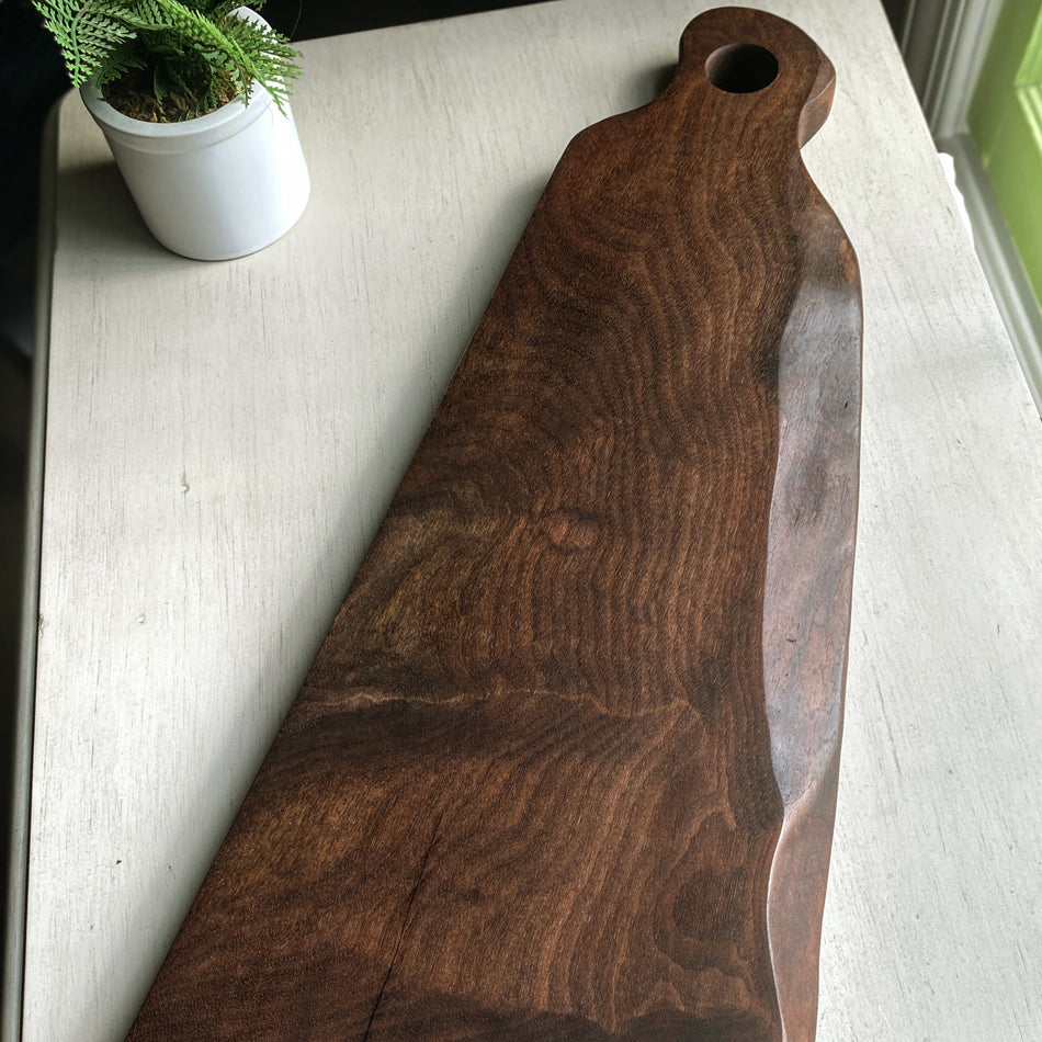 This 22"x10"x1" Charcuterie Board is crafted from Claro Walnut Live Edge and finished with Sutherland Welles Tung Oil. It makes an ideal centerpiece for any table.