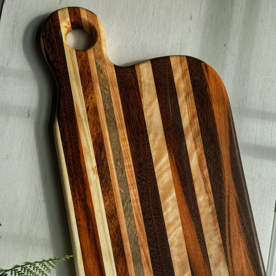 
                  
                    Composed of Tiger Heart, Goncalo Alves and Black Limba, the 19" long, 10" wide, Handcrafted Charcuterie Board is a stunning 1" thick spectacle of contrast and color.
                  
                