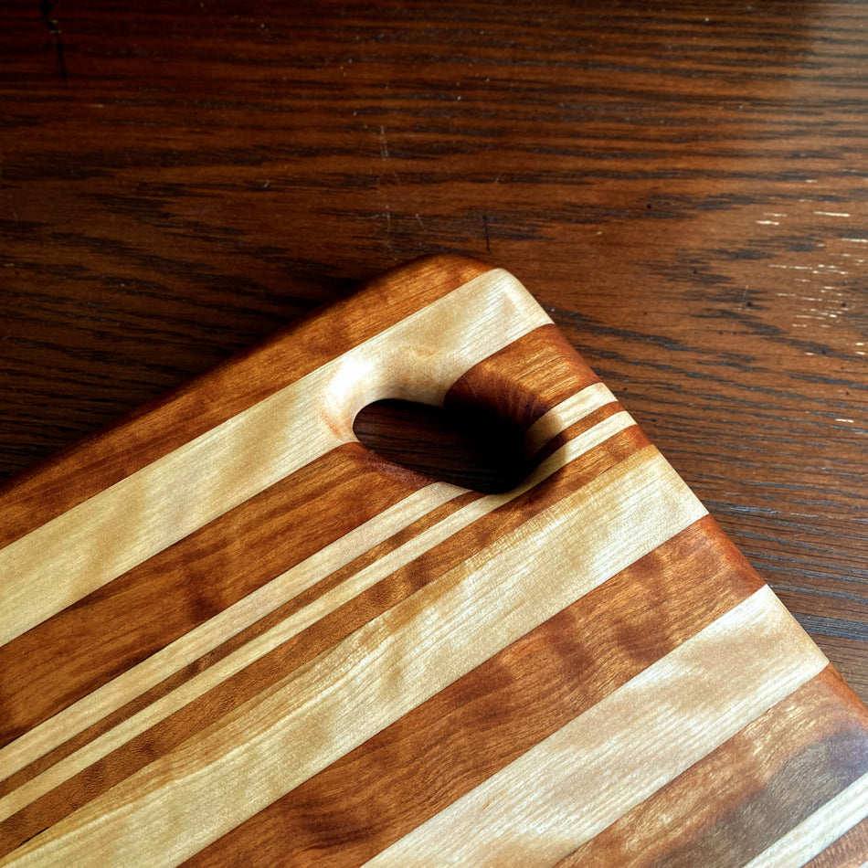 
                      
                        This Charcuterie Board is crafted from Curly Cherry and Tiger Heart. These two wood species are beautiful together. cutting surface. The 17 3/4-inch board delivers ample space to hold meats, cheeses, fruits, and other appetizers, while the 1-inch thickness offers durable rigidity. A Millie's All-Purpose Penetrating Tung Oil finish seals to further reinforce the board's strength and longevity.
                      
                    