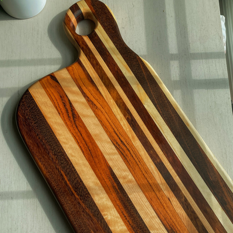 
                  
                    Composed of Tiger Heart, Goncalo Alves and Black Limba, the 19" long, 10" wide, Handcrafted Charcuterie Board is a stunning 1" thick spectacle of contrast and color.
                  
                