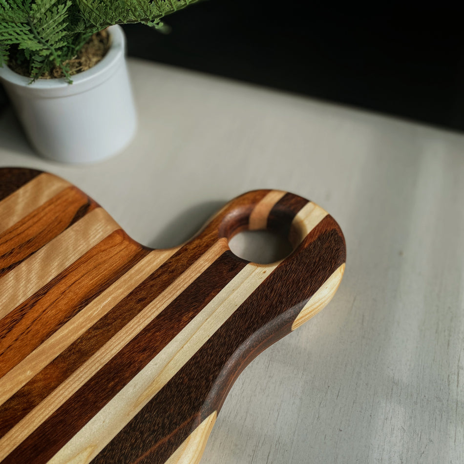 
                  
                    Composed of Tiger Heart, Goncalo Alves and Black Limba, the 19" long, 10" wide, Handcrafted Charcuterie Board is a stunning 1" thick spectacle of contrast and color.
                  
                