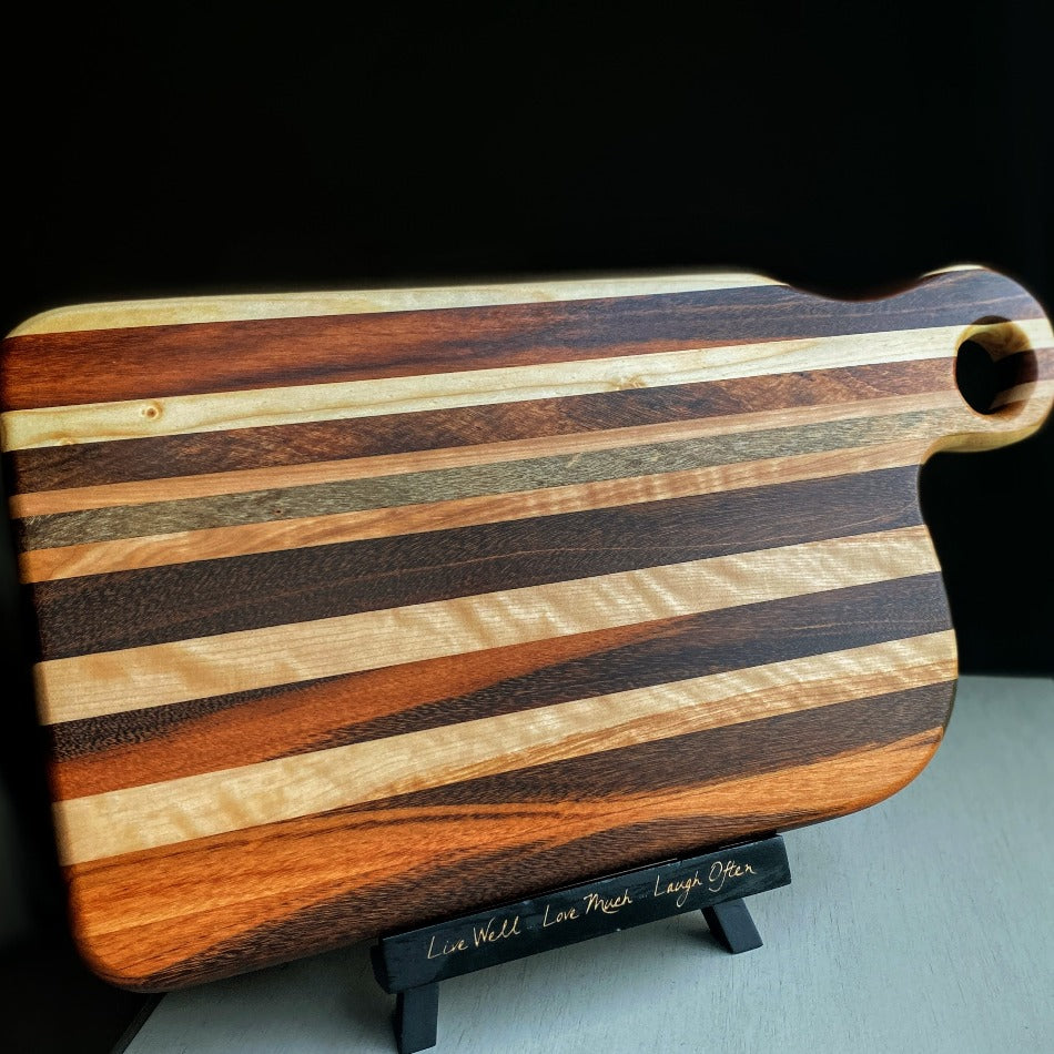 
                  
                    Composed of Tiger Heart, Goncalo Alves and Black Limba, the 19" long, 10" wide, Handcrafted Charcuterie Board is a stunning 1" thick spectacle of contrast and color.
                  
                