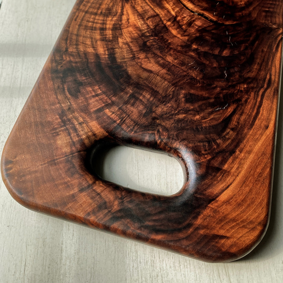 This Handcrafted Charcuterie Board is fashioned from Highly Figured Walnut wood from the Northeastern States. Its generously sized design, measuring 22" Long, 9" wide, and " thick, and weighing nearly 15 pounds, creates an impressive centerpiece for any gathering.