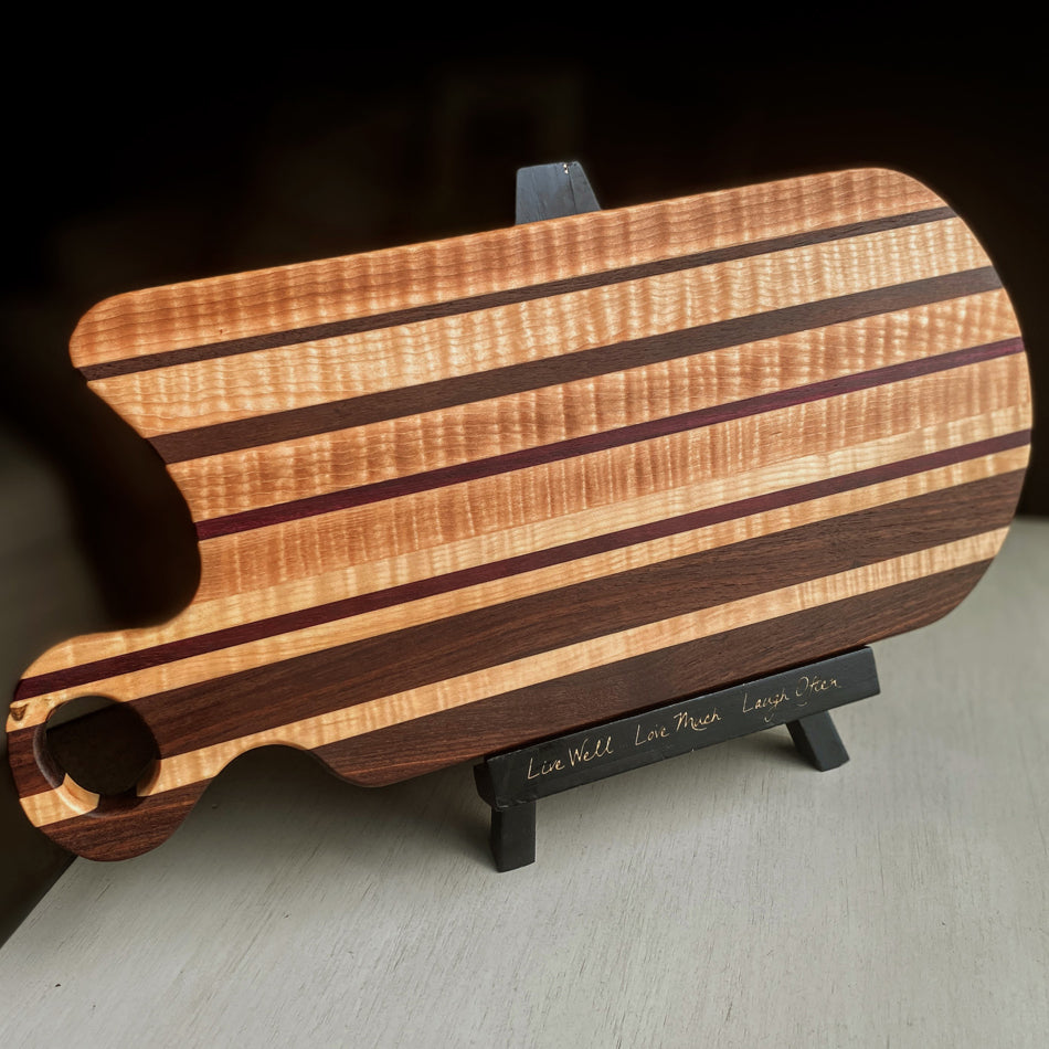 This handcrafted Charcuterie Board is created with Curly Birch, Walnut and Purple Heart with a Millie's All-Purpose Penetrating Tung Oil finish. It measures 17" (including its handle), 7 3/4" wide, and 1" thick, making it ideal for intimate social gatherings.