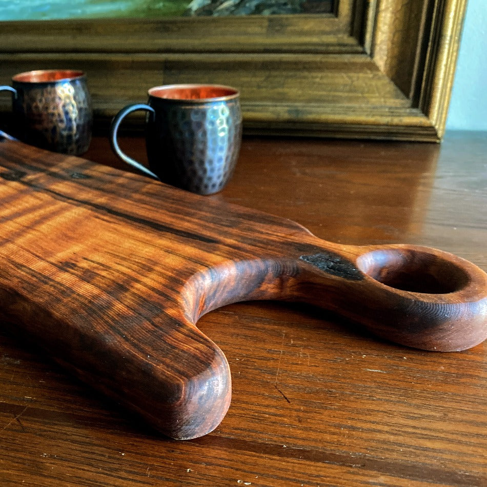 This Charcuterie Board is crafted from Old Growth Redwood live edge to give outstandingly unique color and grain. A real statement piece, it is perfect for entertaining with friends and cocktails on the patio. Seasoned and finished with Milie's Penetrating Tung Oil, it is best used for serving and not cutting.  Presentation on both sides.