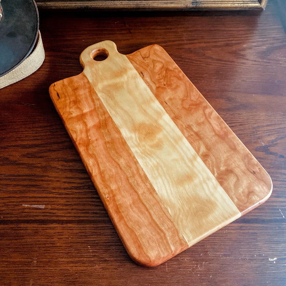 Measuring 18" in length and 13 1/4" in width at a depth of 1", this Charcuterie Board is meticulously handcrafted from Curly Cherry and Curly Birch and finished with Sutherland Welles Ltd.® Botanical Polymerized Tung Oil High Lustre and Bowl & Board™.
