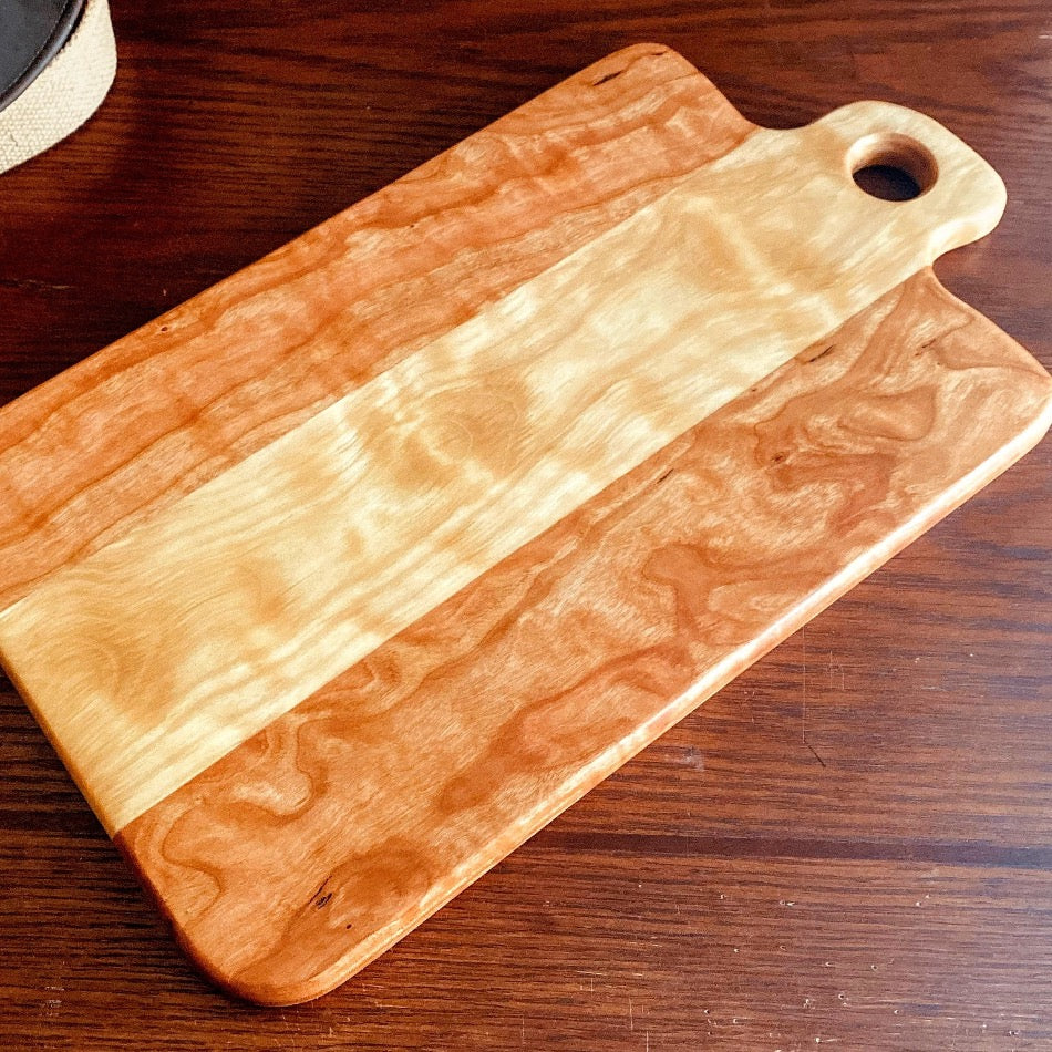 Measuring 18" in length and 13 1/4" in width at a depth of 1", this Charcuterie Board is meticulously handcrafted from Curly Cherry and Curly Birch and finished with Sutherland Welles Ltd.® Botanical Polymerized Tung Oil High Lustre and Bowl & Board™.